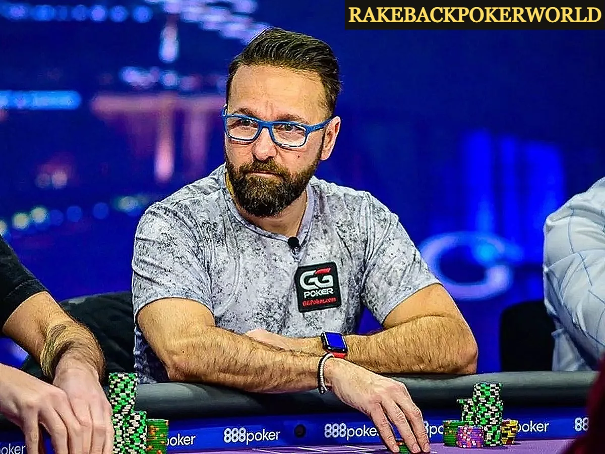 Daniel Negreanu, jogador profissional de pôquer, está sentado à mesa durante um torneio, usando camiseta cinza, óculos de armação azul e relógio digital. Fichas de pôquer estão empilhadas à sua frente, com o logotipo do 888poker visível na mesa. Ao fundo, o ambiente mostra luzes desfocadas de um cassino. - rakebackpokerworld.com